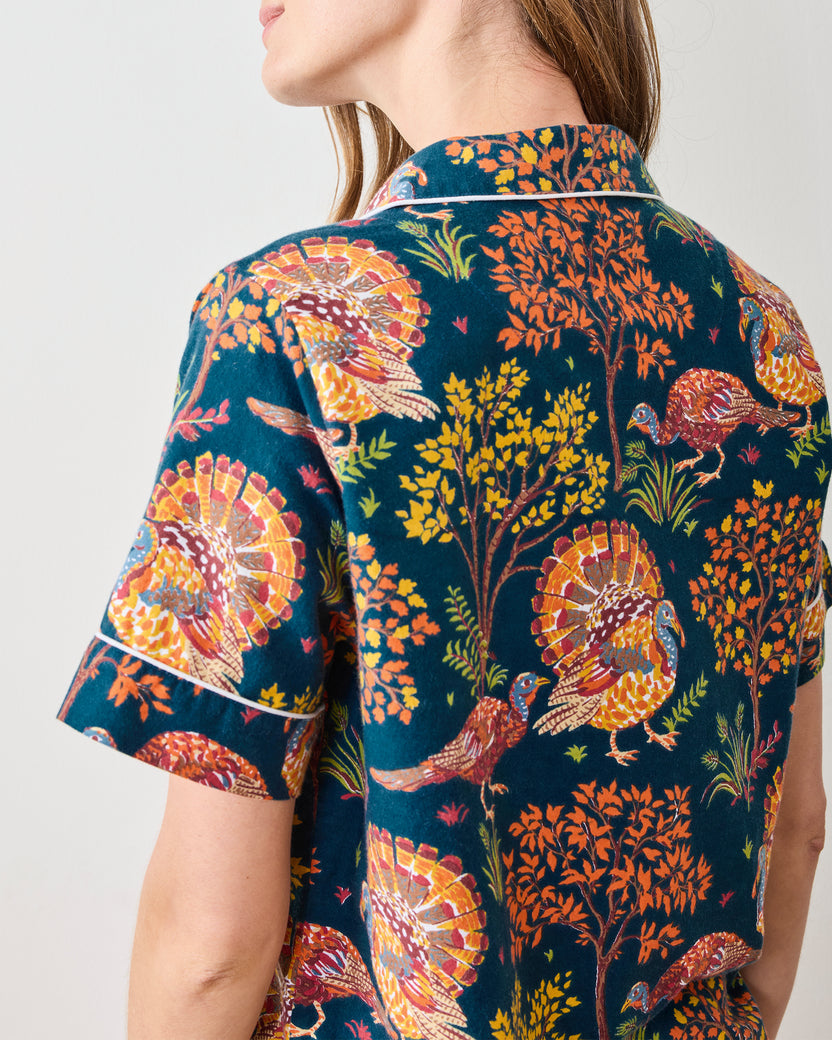 Close-up back view of the navy pajama top showing the turkey and autumn foliage print, collar, and sleeve trim.