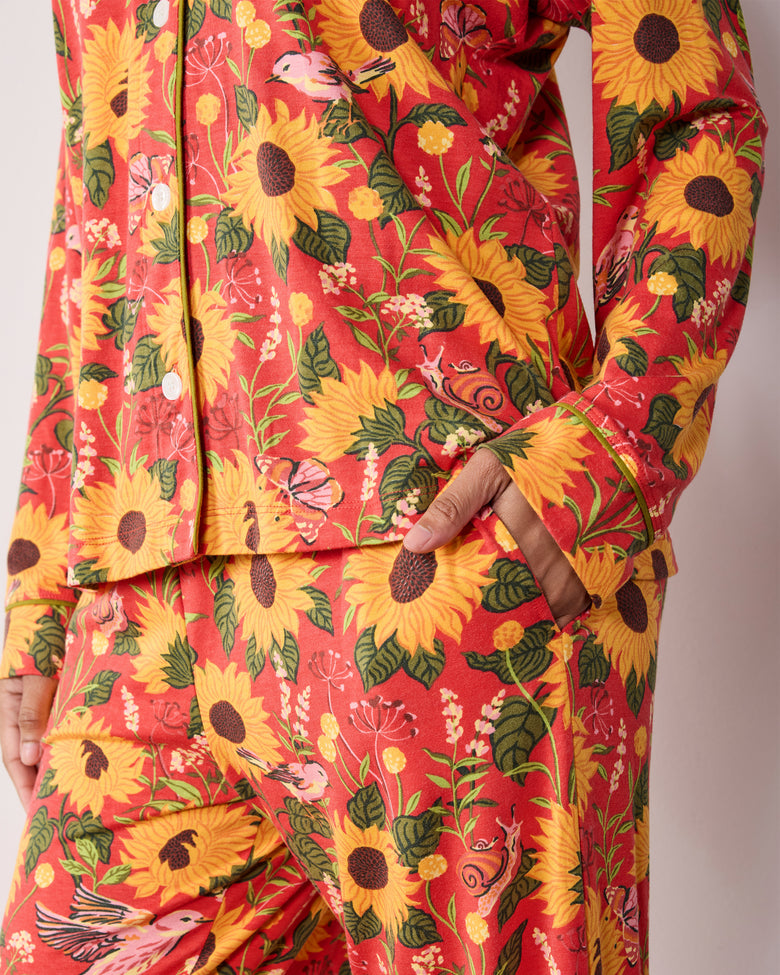 Close view of the orange Autumn Sunflowers long pajama set, showing the floral print, button-front top, sleeve cuff, and pants pocket.