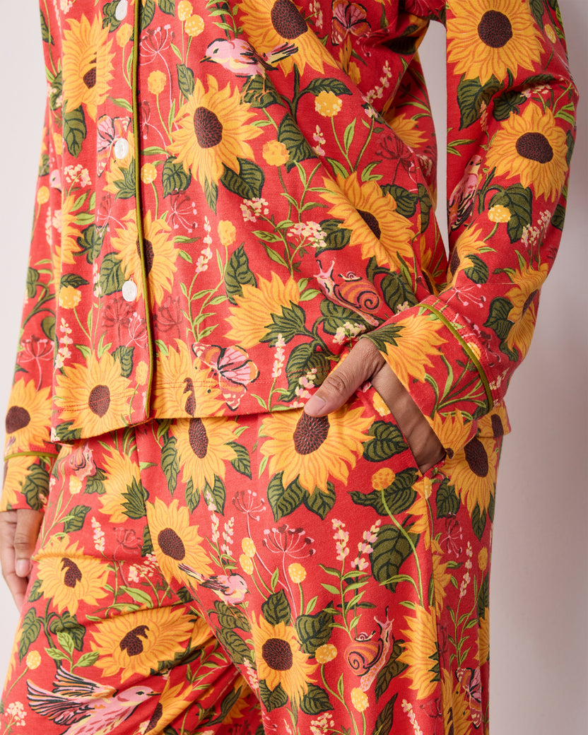 Close view of the orange Autumn Sunflowers long pajama set, showing the floral print, button-front top, sleeve cuff, and pants pocket.