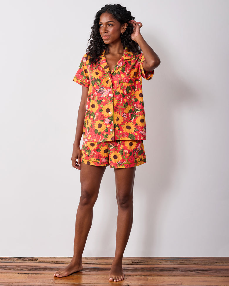 Model wearing the orange Autumn Sunflowers short pajama set, shown from the front with one hand touching her hair.