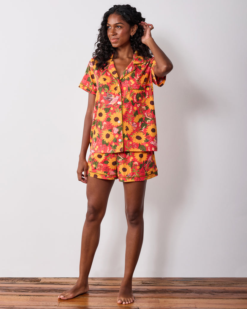 Model wearing the orange Autumn Sunflowers short pajama set, shown from the front with one hand touching her hair.