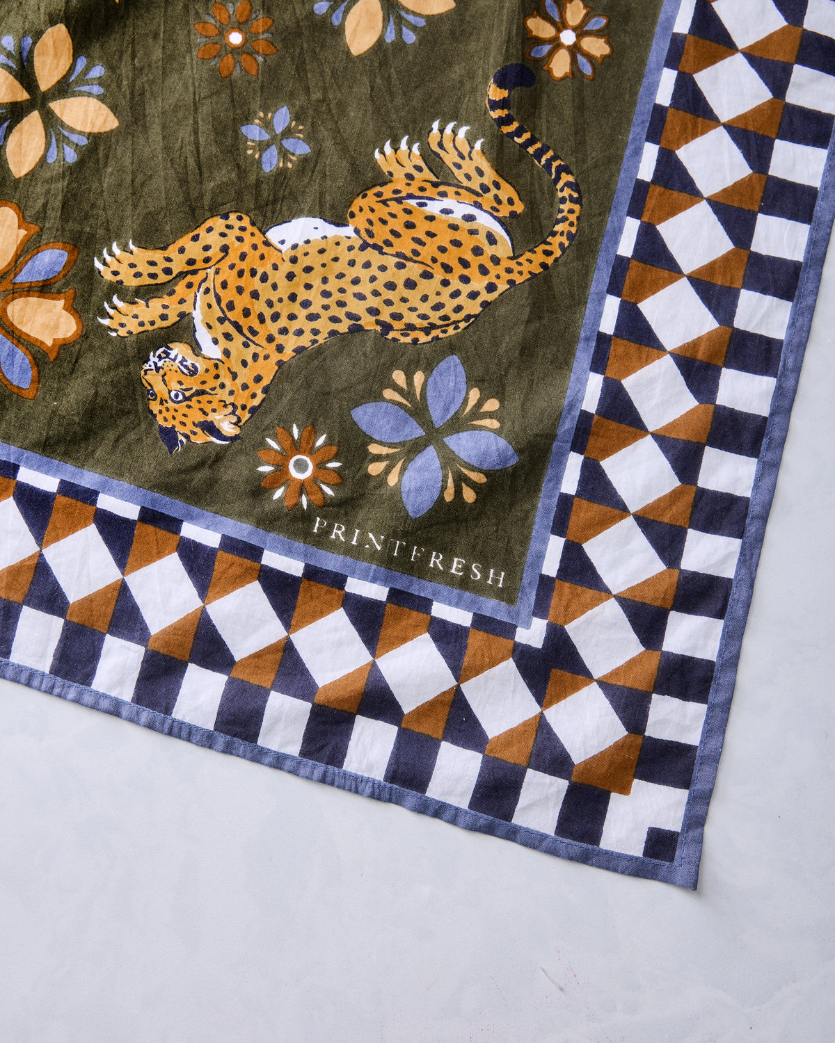 Close-up of the Bagheera Kaleidoscope scarf showing a leopard illustration, floral motifs, and geometric border