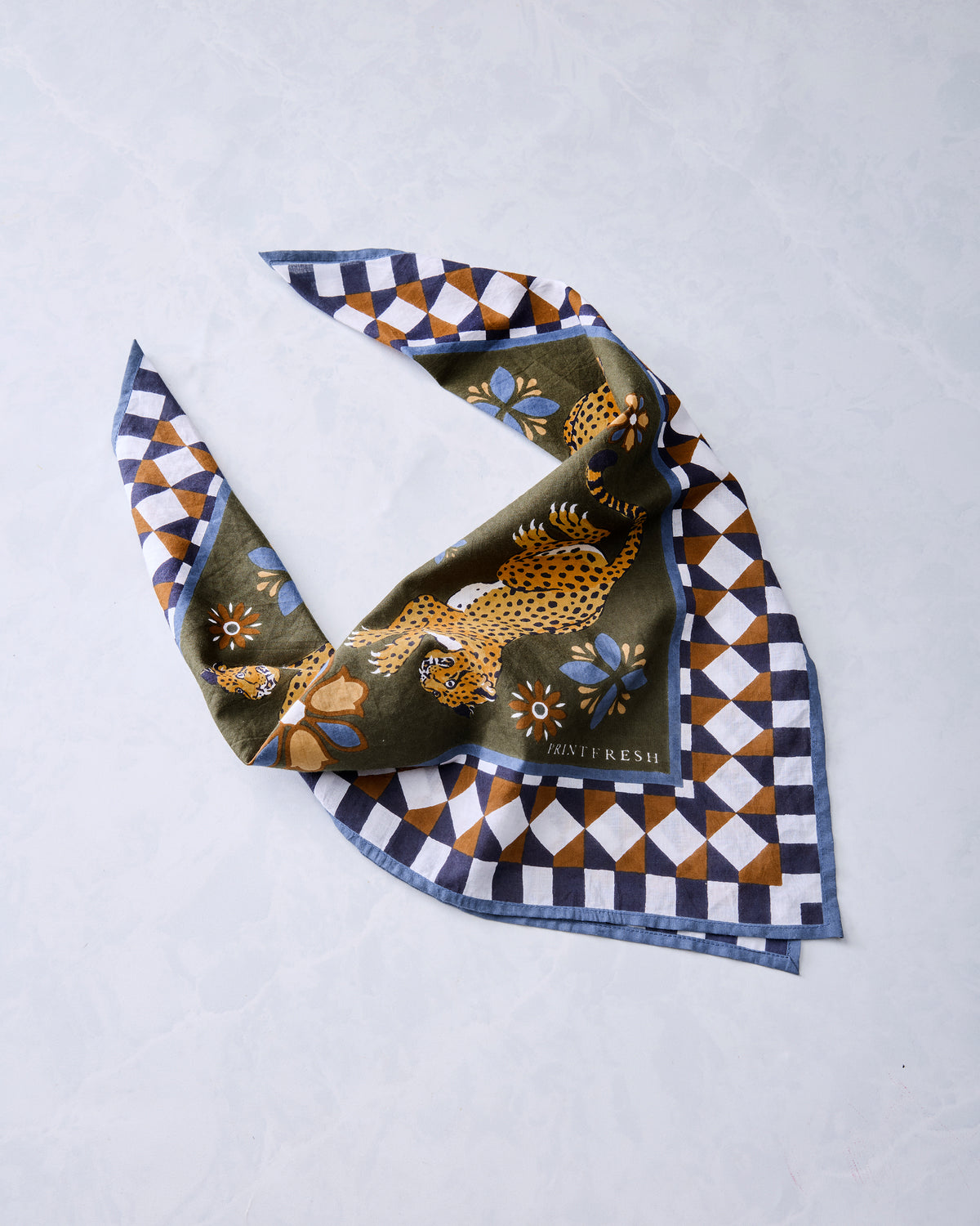 Olive bandana scarf loosely folded to show its leopard, floral, and geometric border print