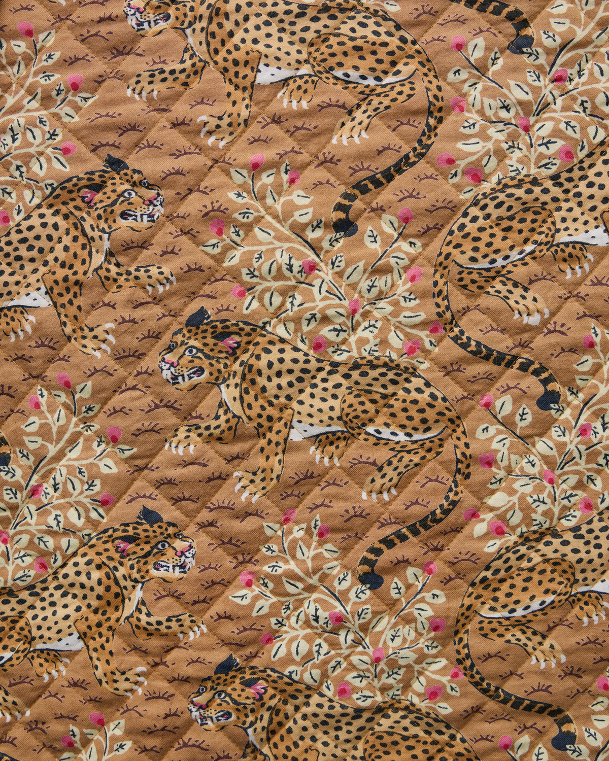 Close-up of tan fabric with repeated leopard illustrations and flowering branches.