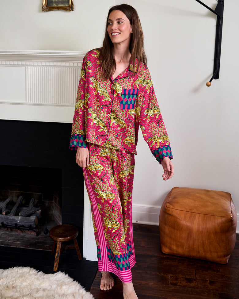 Person standing indoors wearing the Hot Pink Bagheera long-sleeve pajama set with leopard print, wide-leg pants, and contrasting geometric trim.