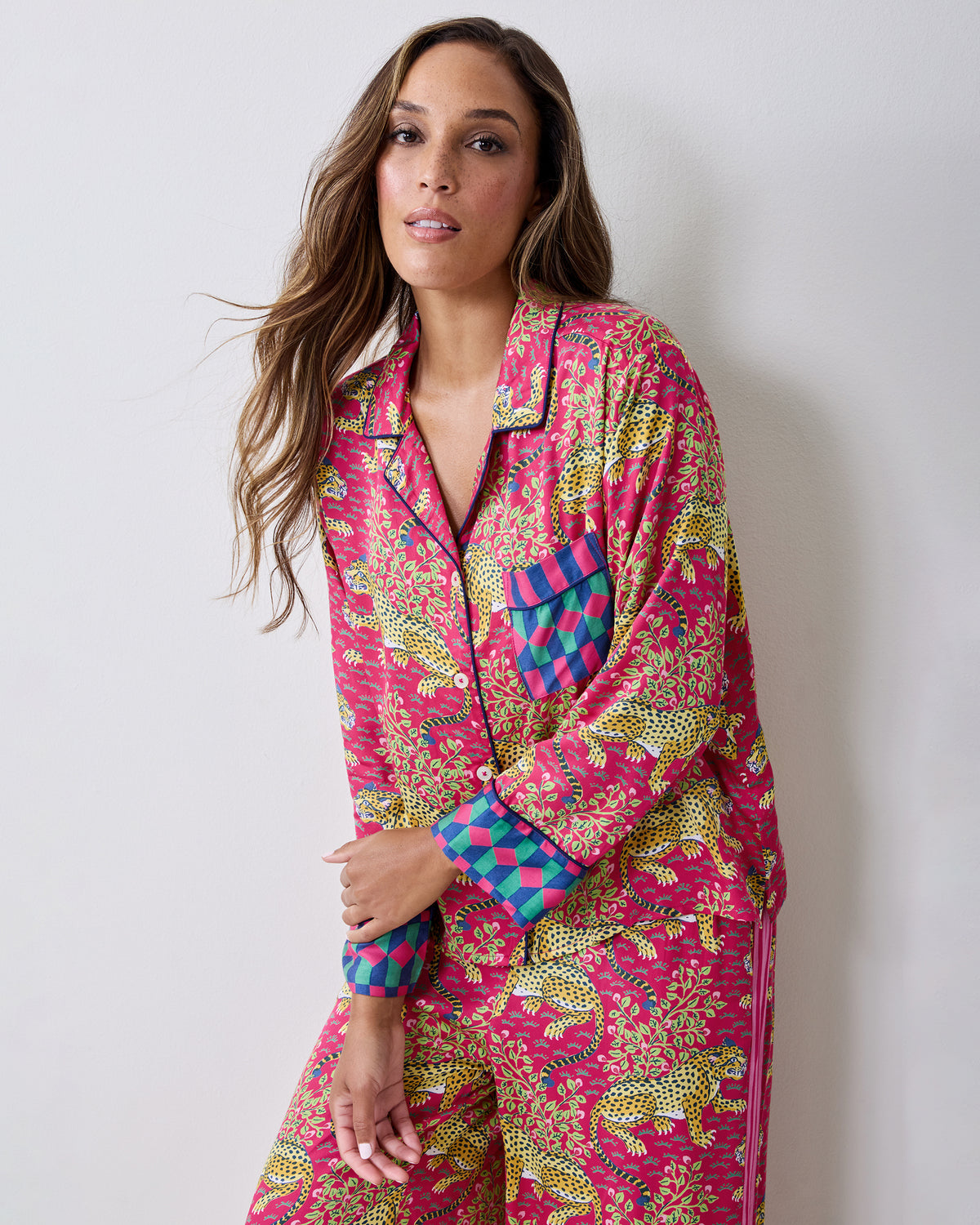 Angled view of a hot pink long-sleeve pajama shirt and wide-leg pants set with leopard and foliage print.
