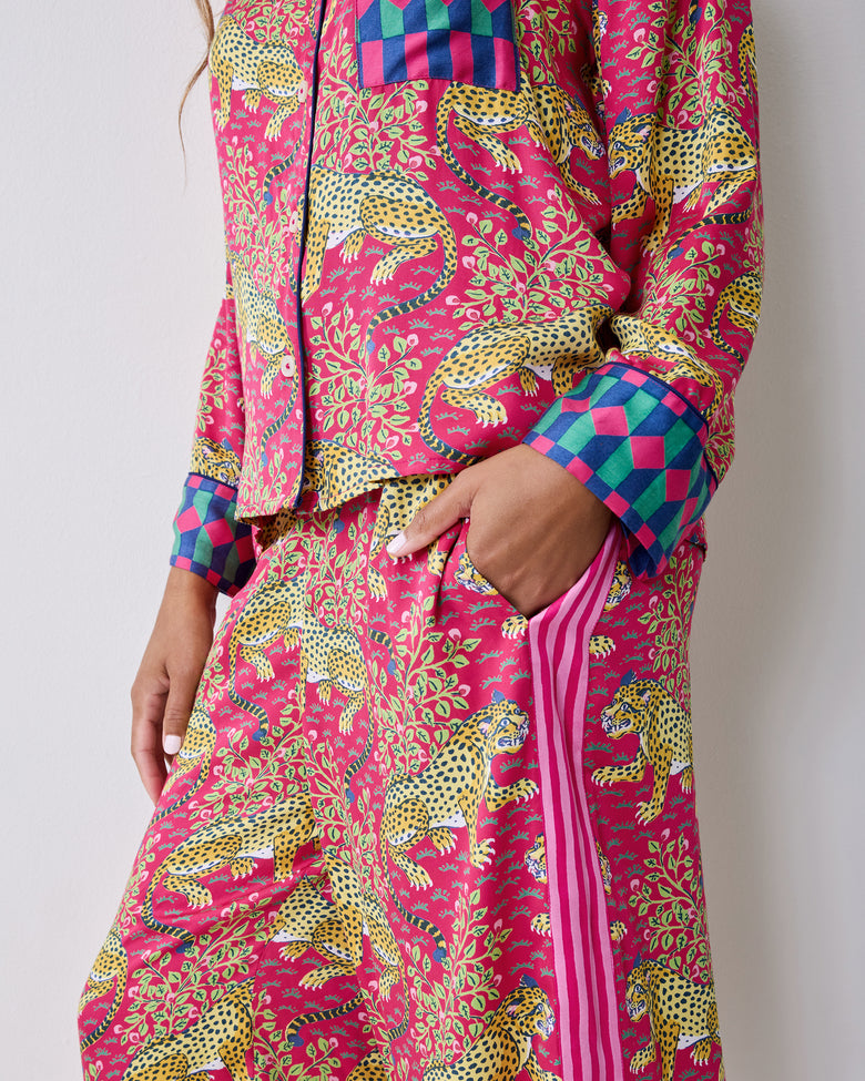 Close-up of the hot pink Bagheera pajama set showing the leopard-and-vine print, geometric cuff, chest pocket, and pants pocket.