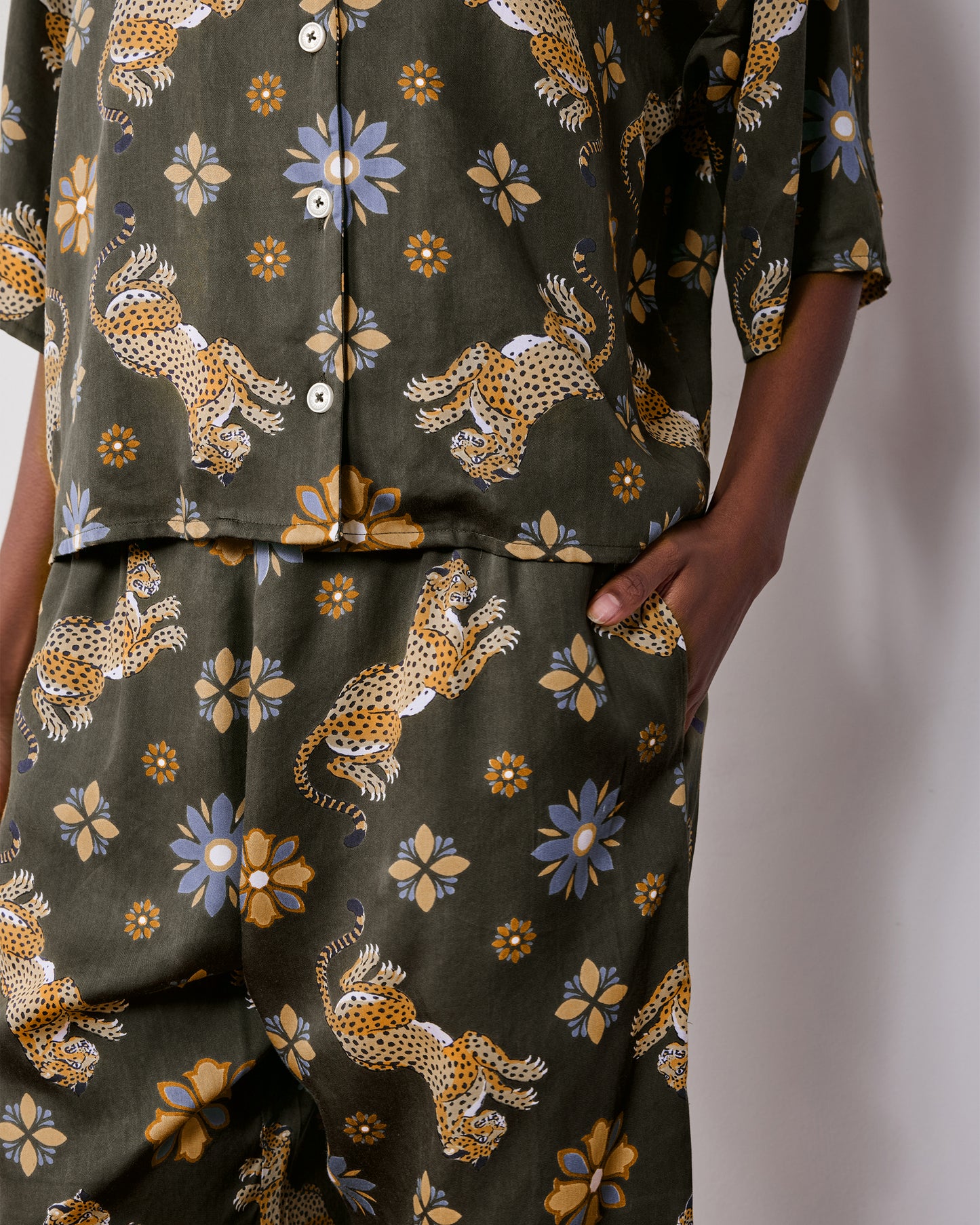 Close view of the olive Wildest Dreams pajama shirt and matching pants, showing the leopard and flower print and side pocket.