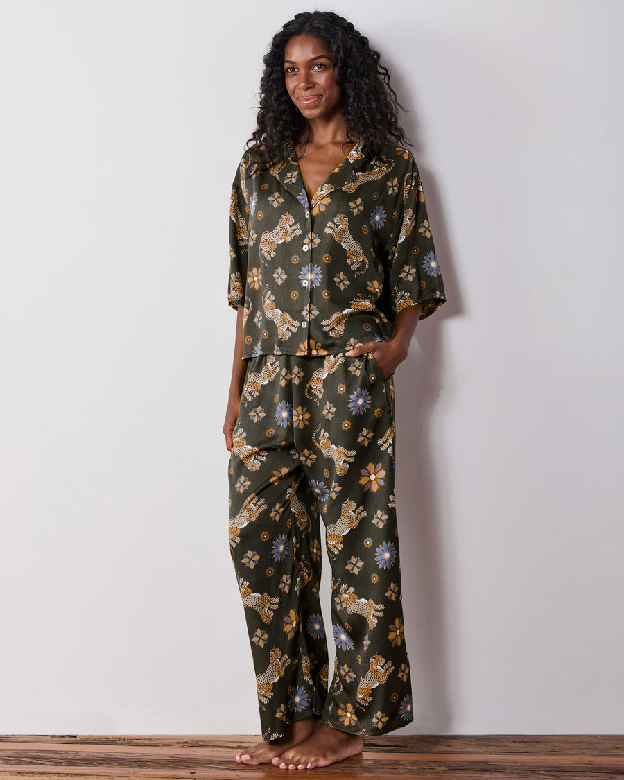 Front view of the olive Wildest Dreams pajama set with a short-sleeve button-front shirt and wide-leg pants covered in leopard and flower prints.