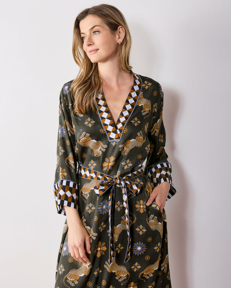 Front view of the olive Bagheera Kaleidoscope Kennedy caftan tied at the waist, showing its V-neck, wide cuffs, side pocket, and leopard-and-flower print.