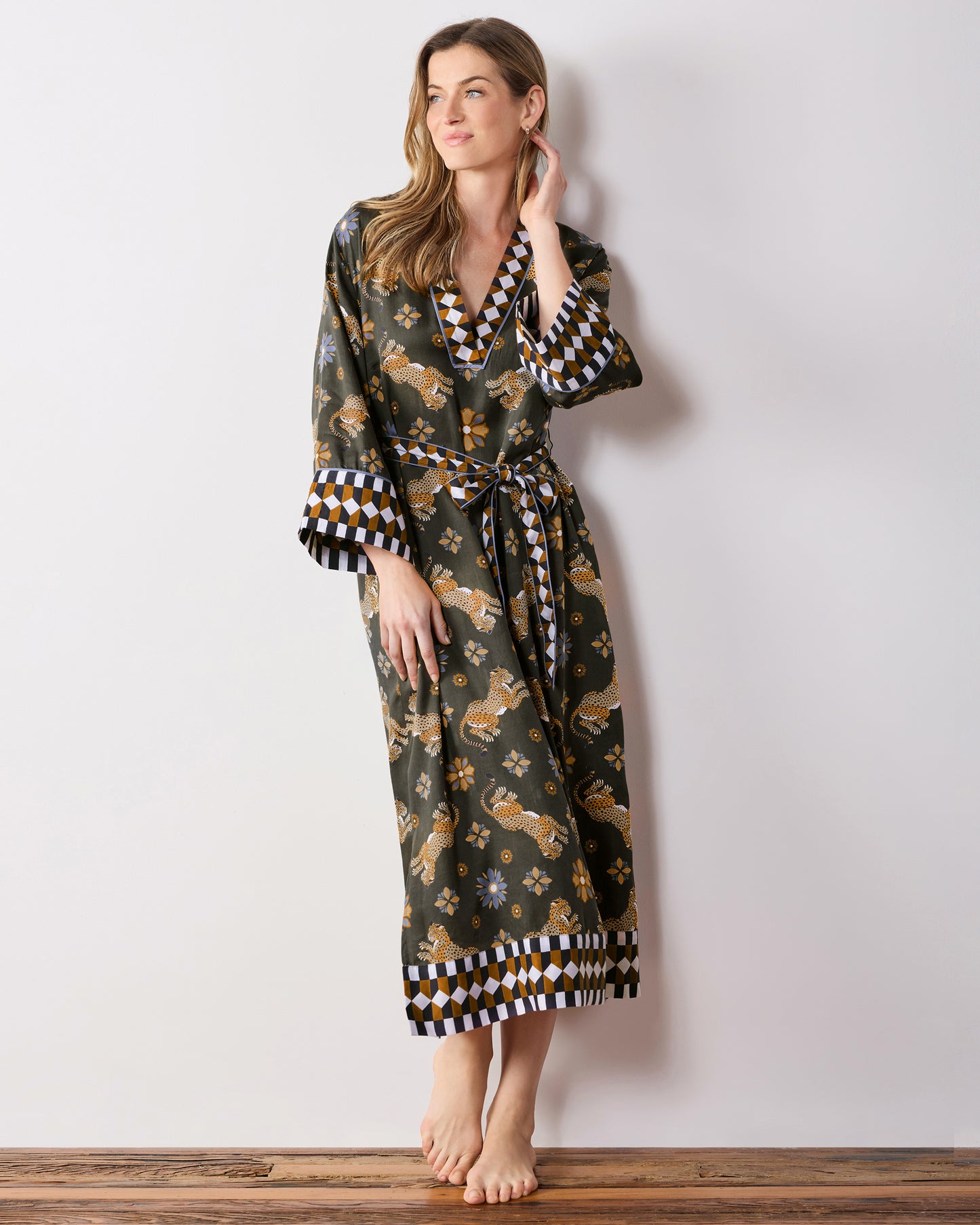 Full-length view of a person wearing an olive caftan with leopard and floral print and geometric trim.