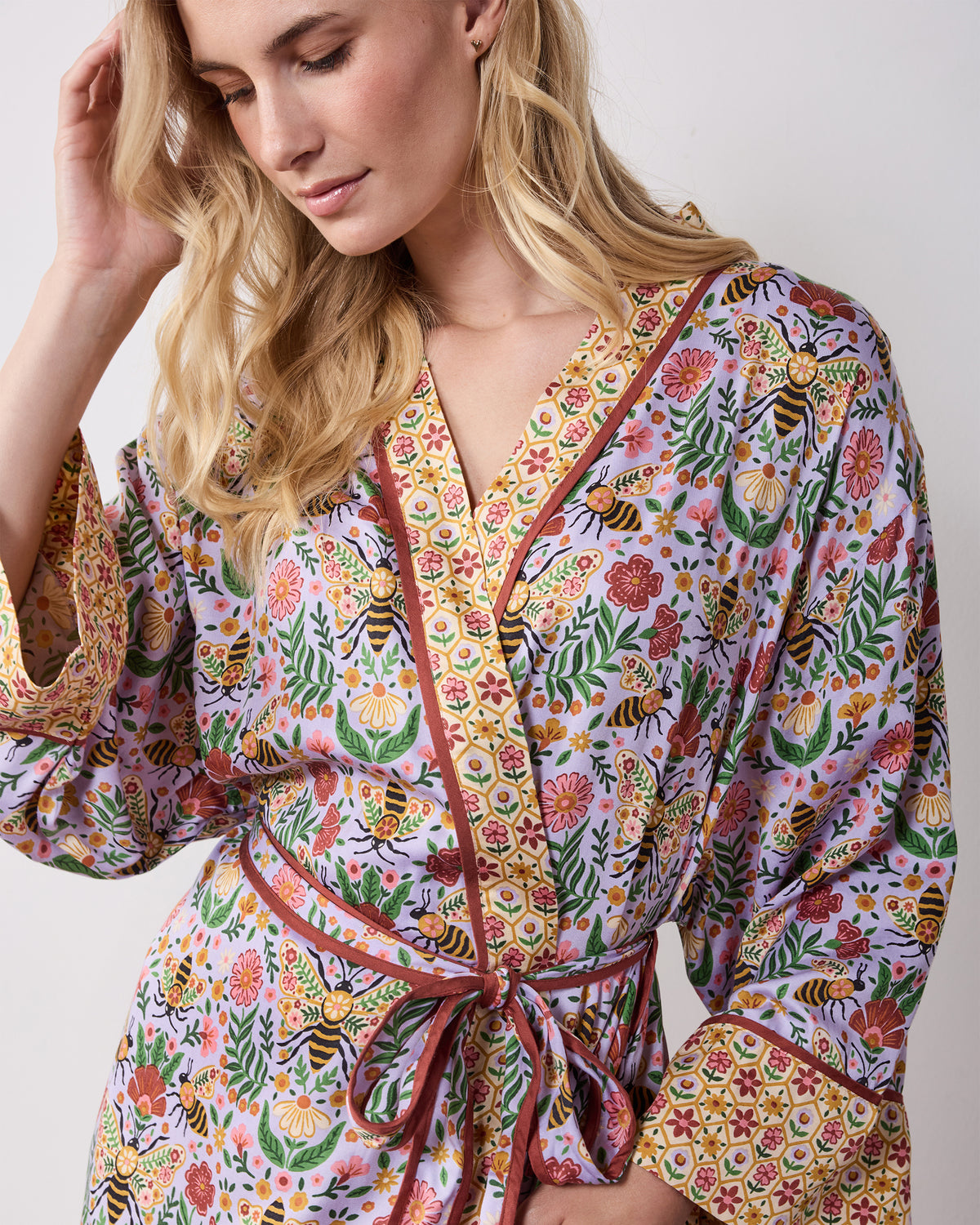 Close-up of the lavender Bee Tapestry robe showing its V-neckline, contrasting trim, floral bee print, and cuff.