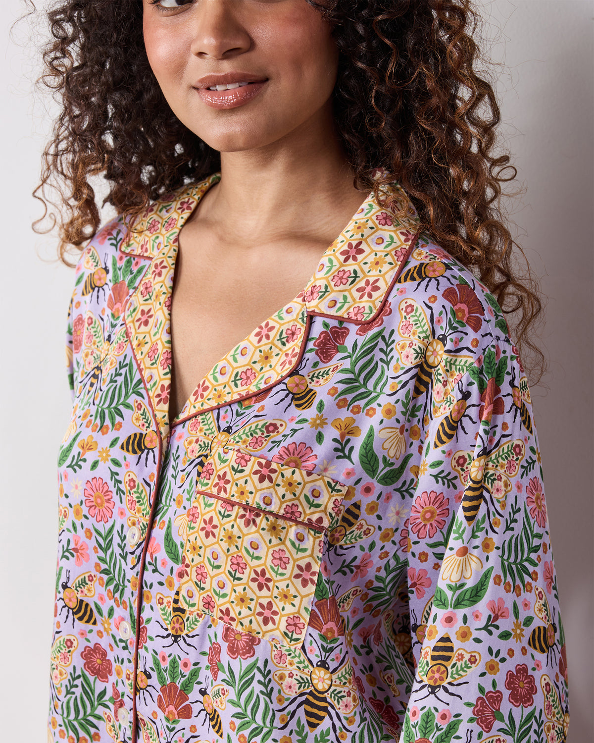 Close-up of the lavender Bee Tapestry pajama top with a floral and honeybee print, contrasting patterned collar, cuffs, and chest pocket.