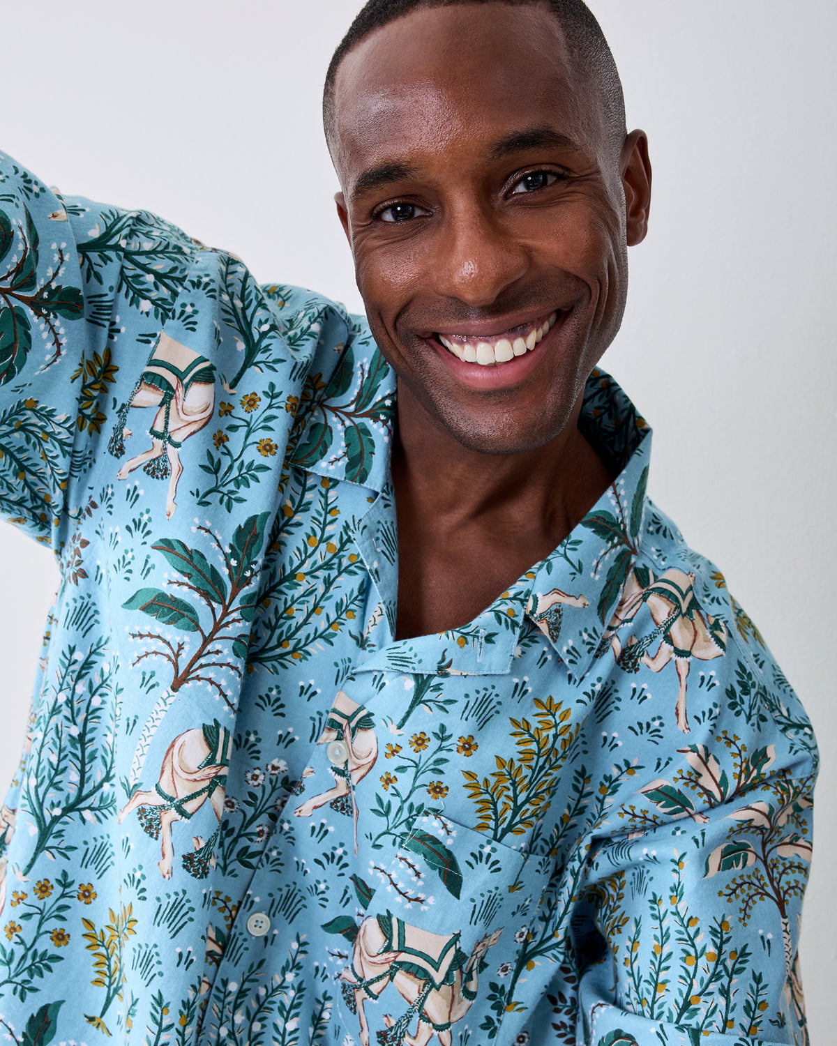 Close-up front view of a model wearing the Slate Blue Camel's Courtyard flannel pajama top with camel and botanical print.