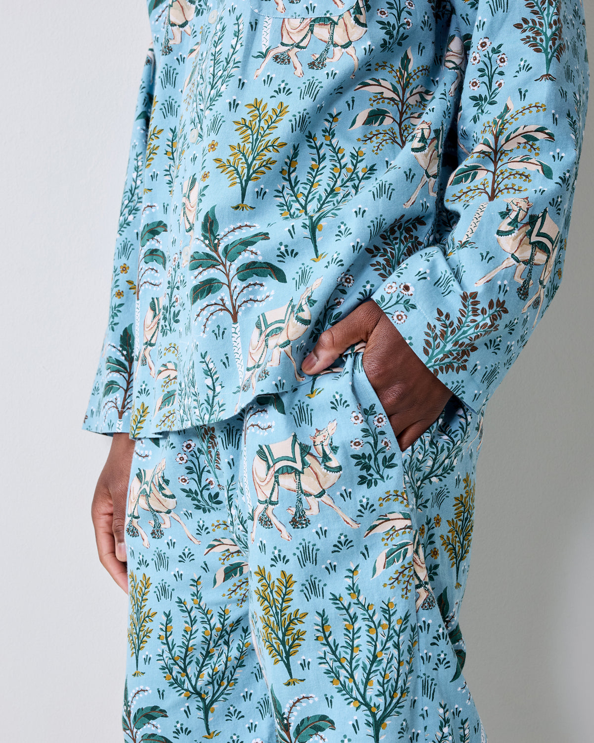 Close-up view of the Slate Blue Camel's Courtyard pajama top and pants, showing the botanical and camel print and a pants pocket.
