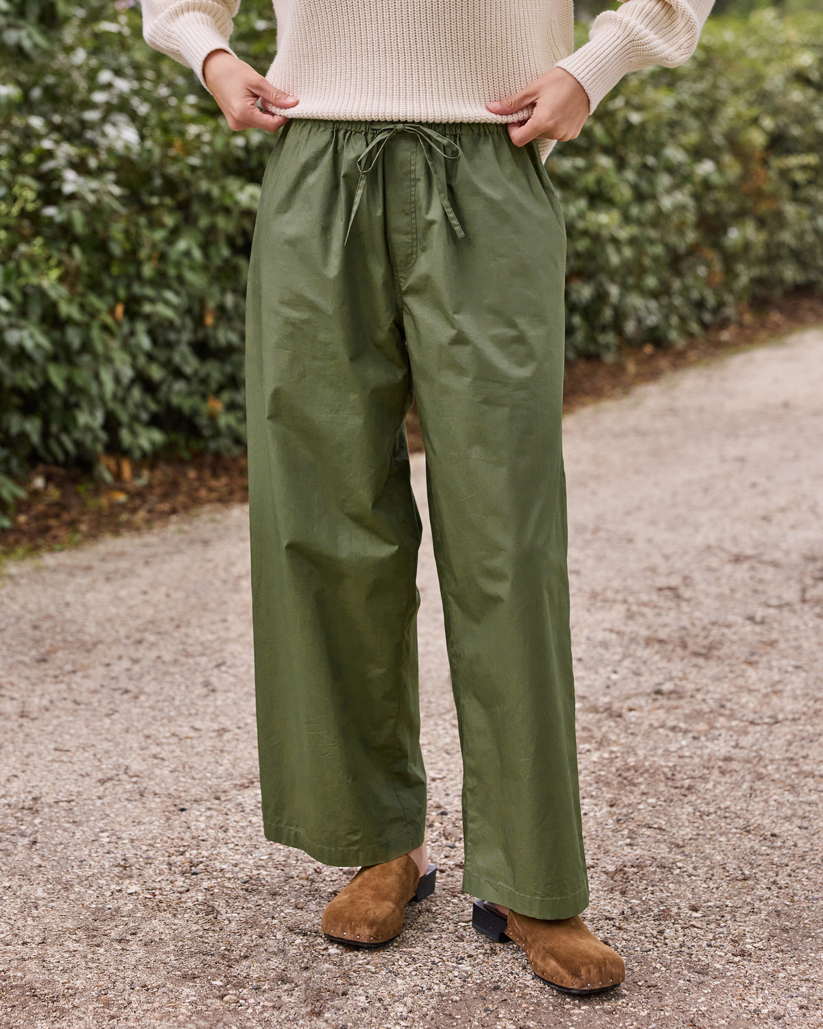 Front view of olive wide-leg pants with an elastic drawstring waist and side pockets, worn with a cream sweater.