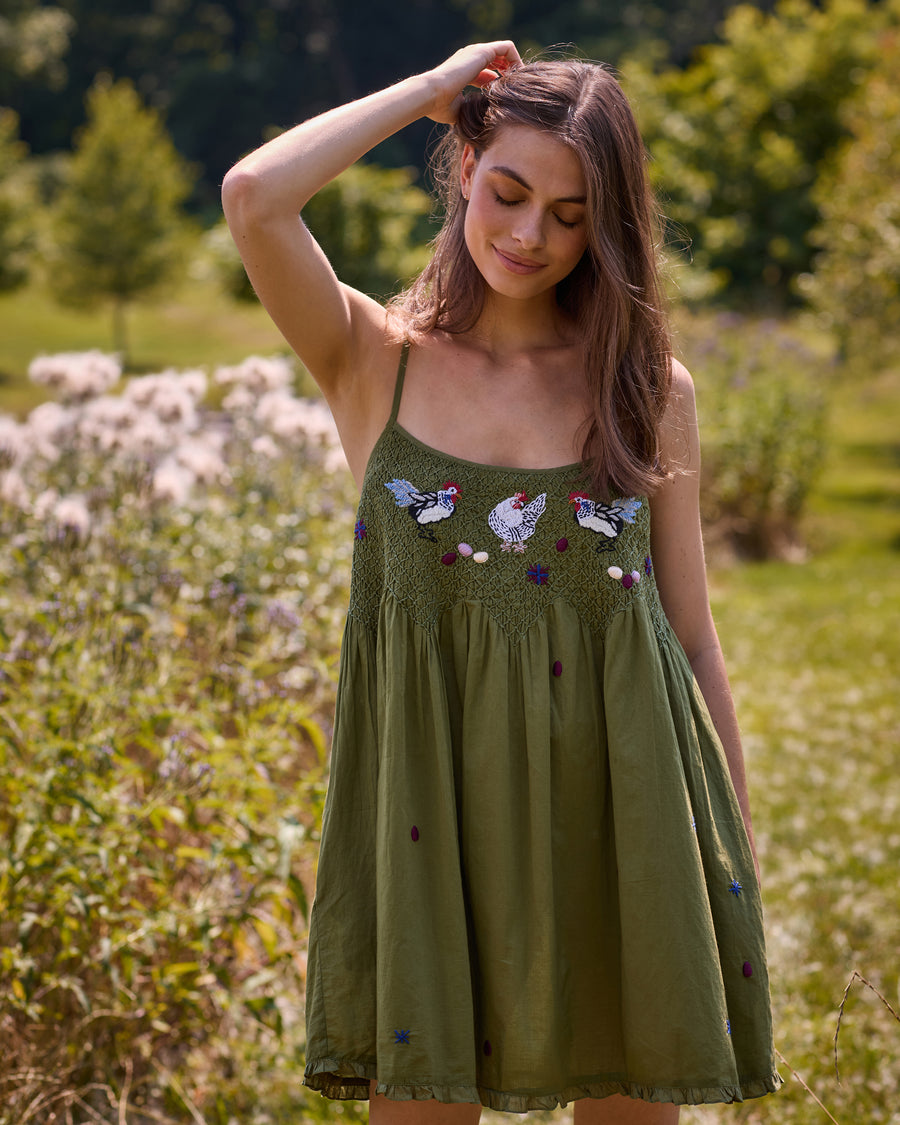 Front view of the Chickens & Roosters Tulsi nightie with an olive background, chicken print, thin shoulder straps, and gathered skirt.