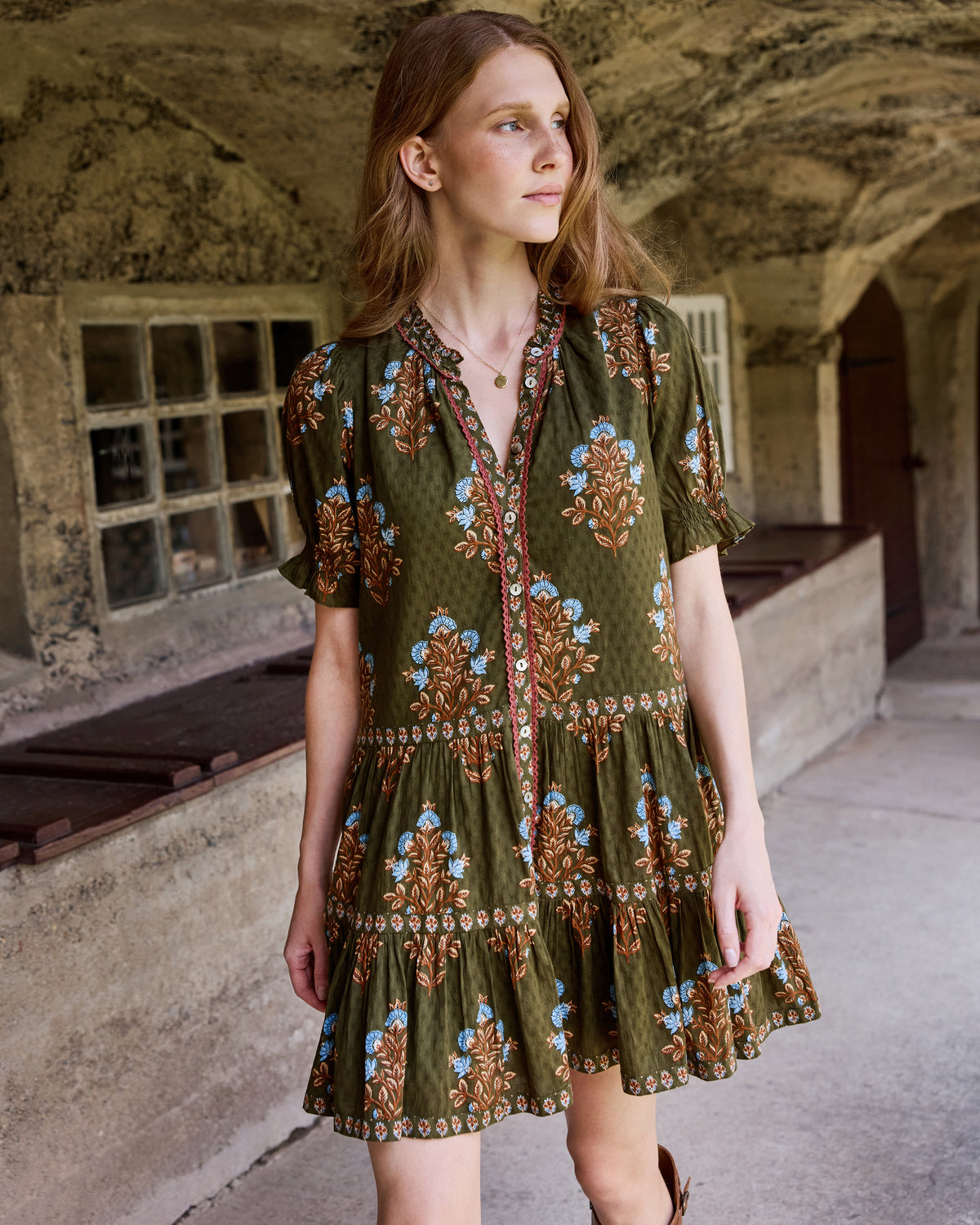 Front view of the Colorado Wildflowers Bella Dress in deep olive, with a floral print, buttoned V-neckline, short sleeves, and tiered skirt.