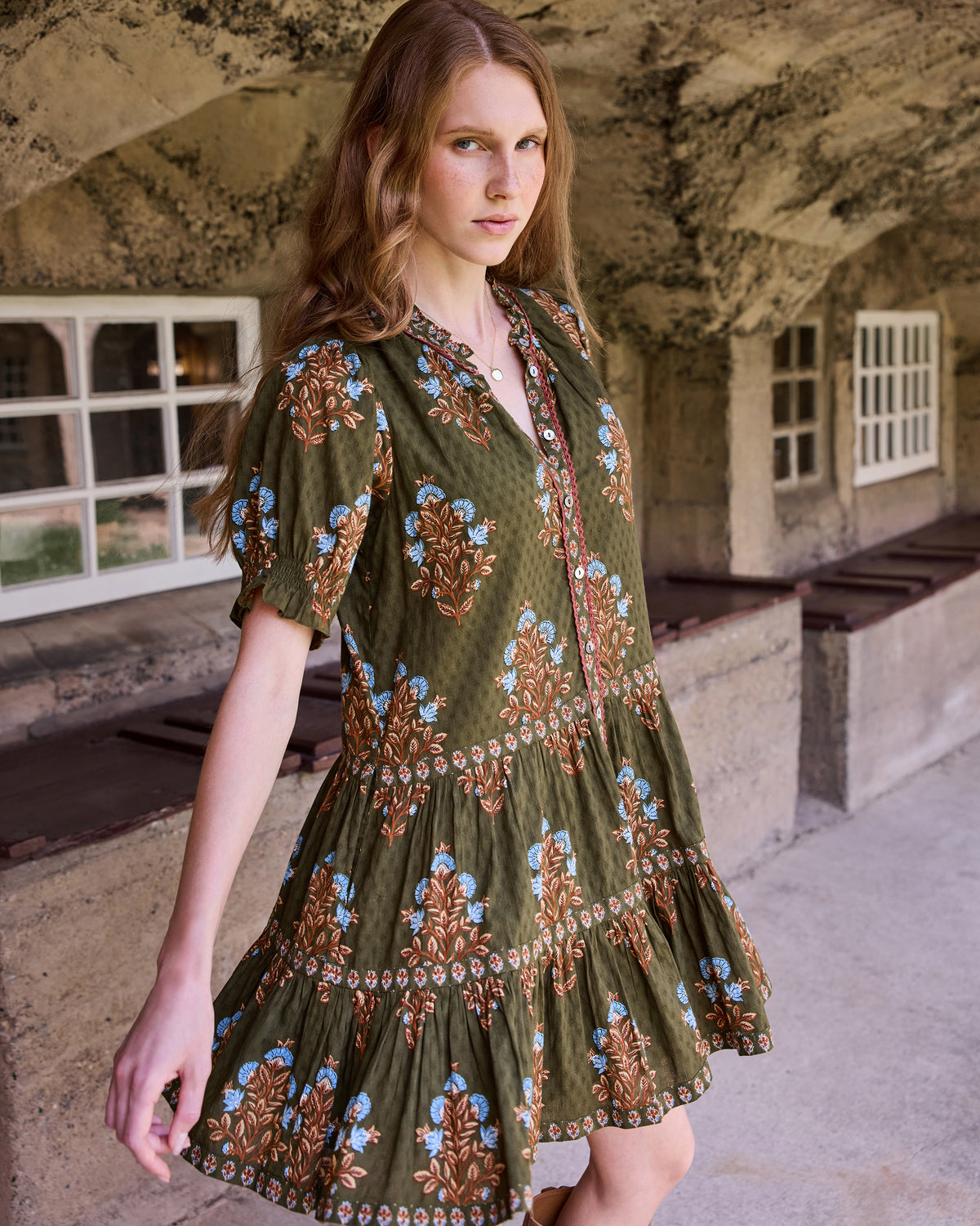 Front three-quarter view of the Colorado Wildflowers Bella Dress, showing the floral print, buttoned neckline, short sleeves, and tiered skirt.