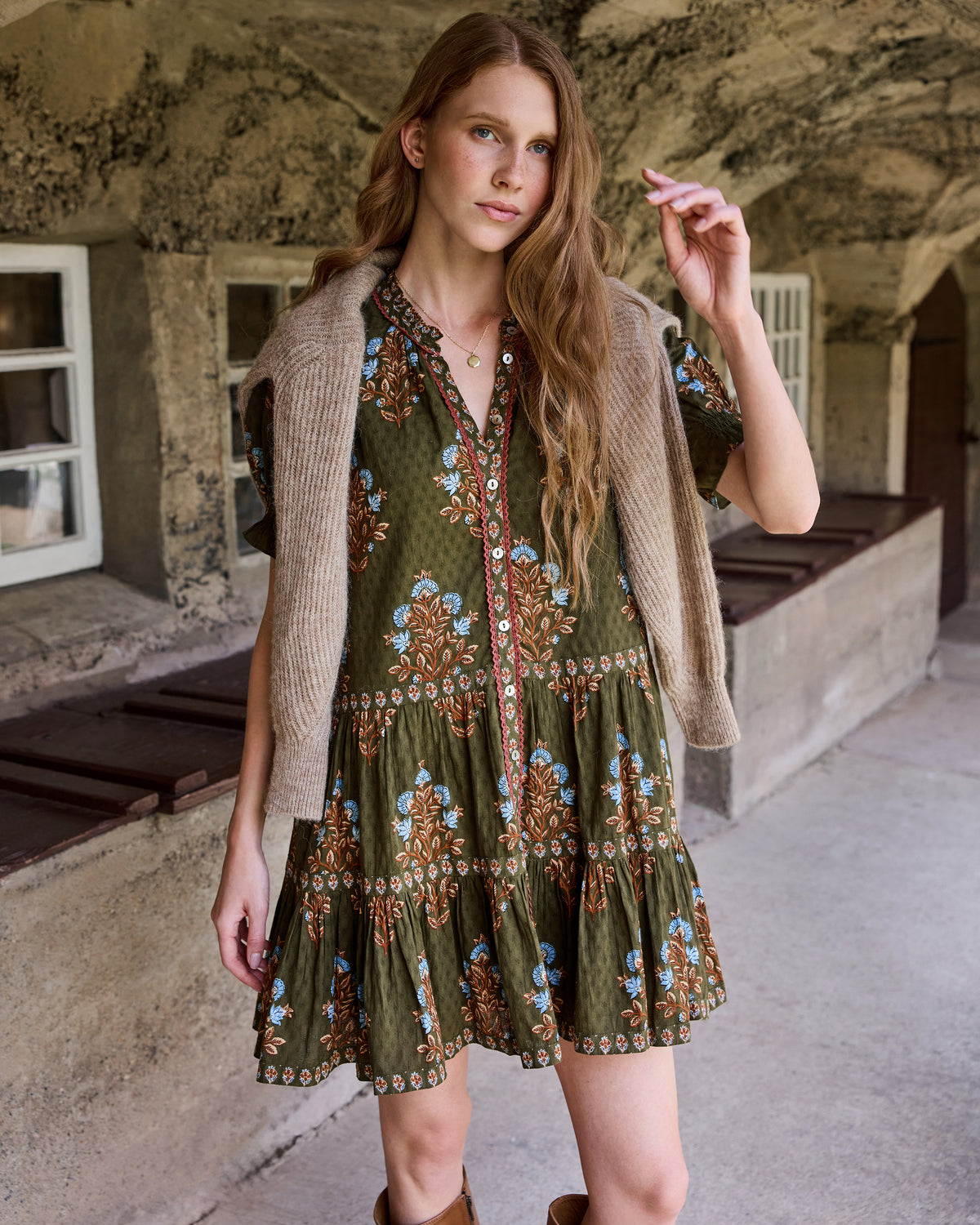 Front view of the Colorado Wildflowers Bella Dress styled with a sleeveless beige cardigan, showing the floral print, buttoned neckline, and tiered skirt.