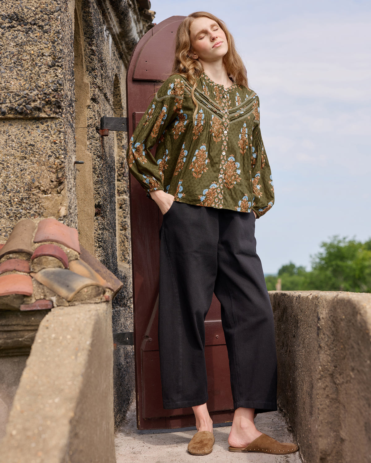 Colorado Wildflowers Belmont Blouse in deep olive with long sleeves and a floral print, styled with black wide-leg pants.