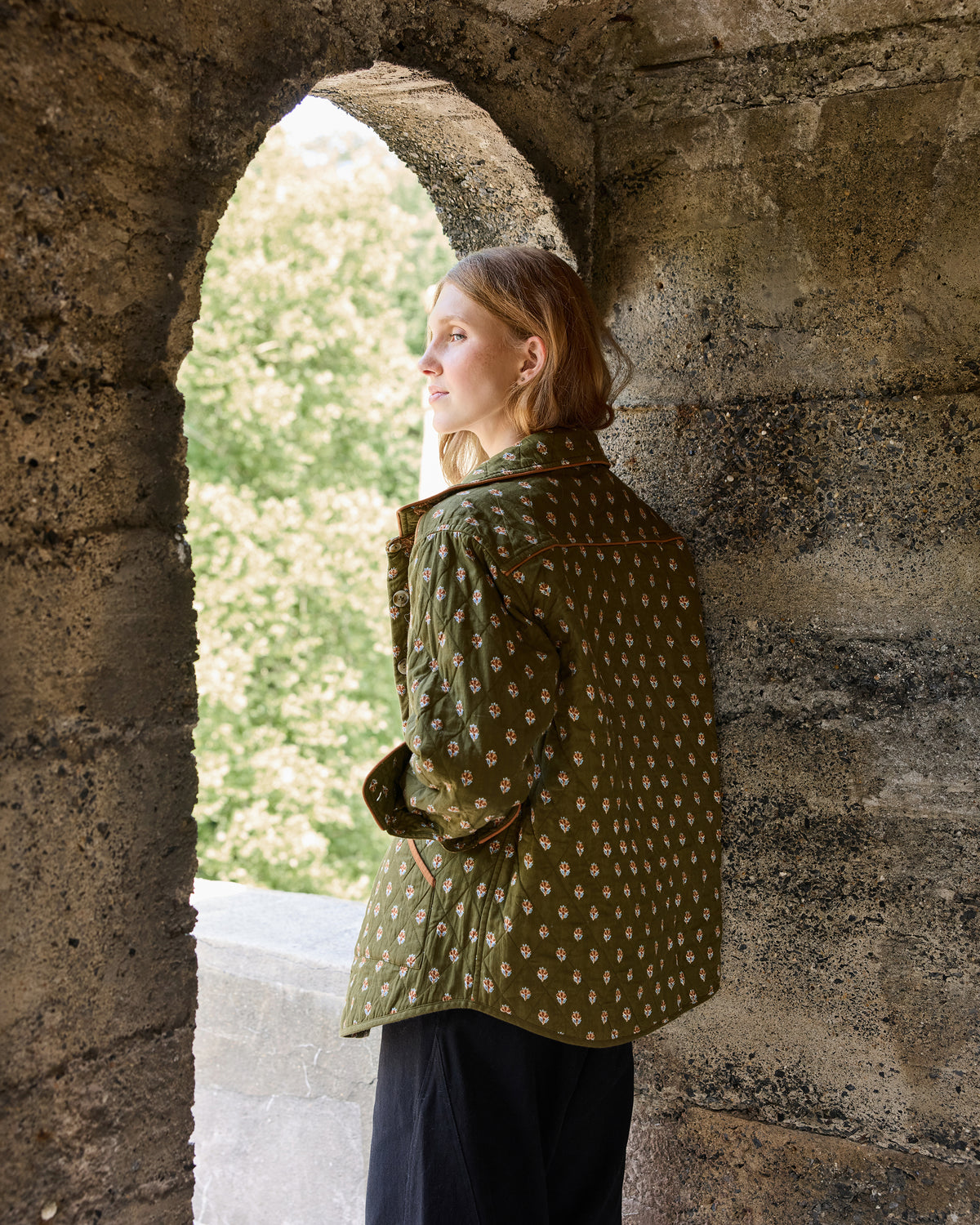Deep olive quilted jacket shown from the back with a small repeating floral print.