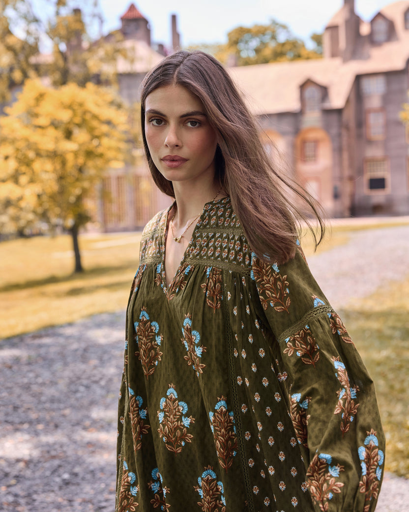 Close view of the deep olive Tallulah dress showing its V-neckline, patterned yoke, and long floral-print sleeves.