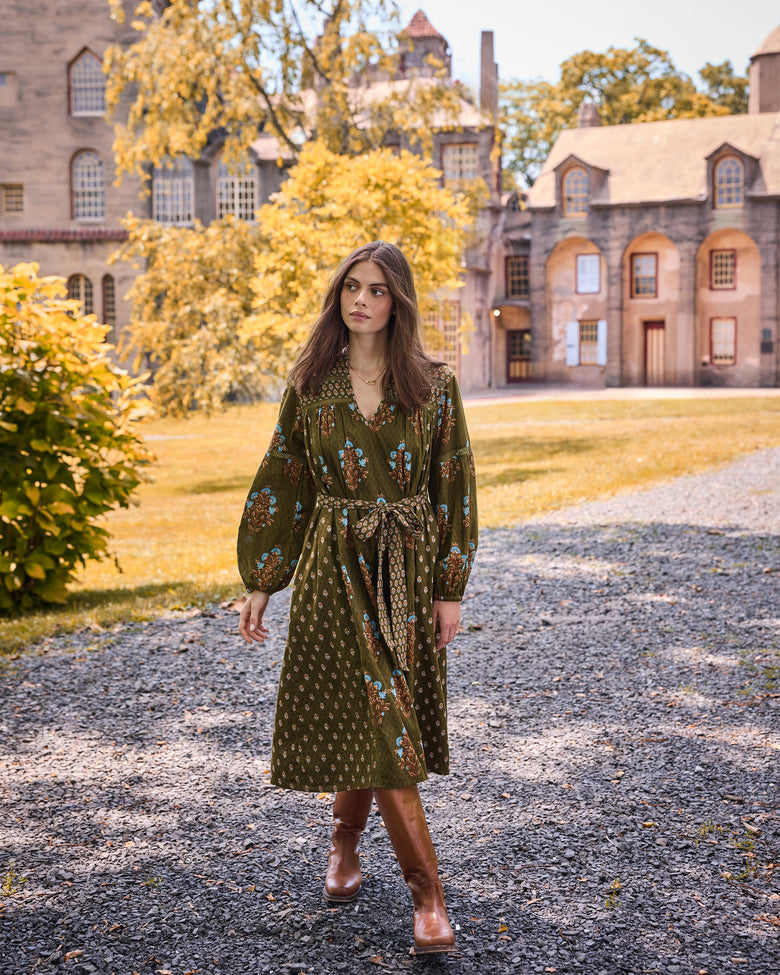 Full front view of the deep olive Tallulah dress with long sleeves, floral print, and a tied waist sash.
