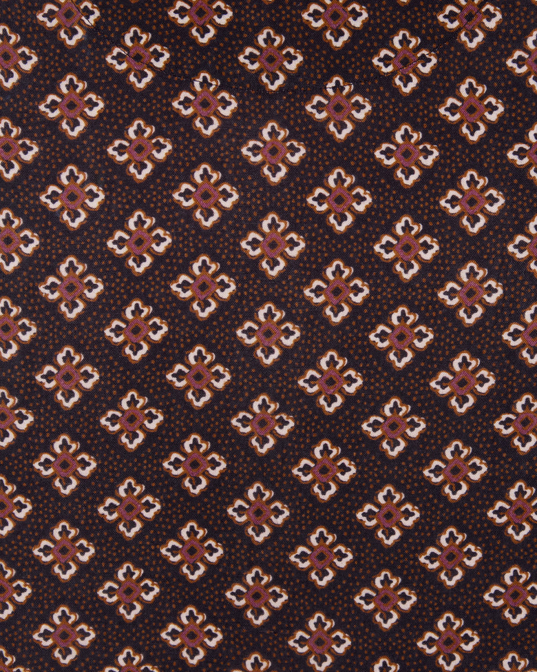 Close-up of dark brown fabric with repeating small geometric floral motifs in white, pink, and brown.