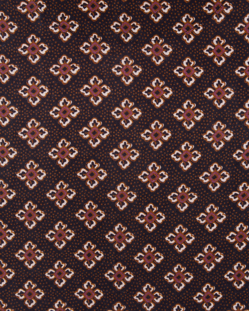 Close-up of dark brown fabric with repeating small geometric floral motifs in white, pink, and brown.