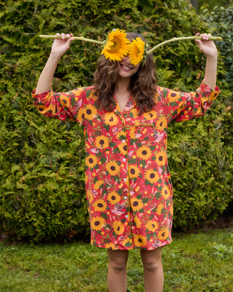 Person wearing the orange floral sleep shirt with arms raised, showing the button front, long sleeves, and chest pocket.