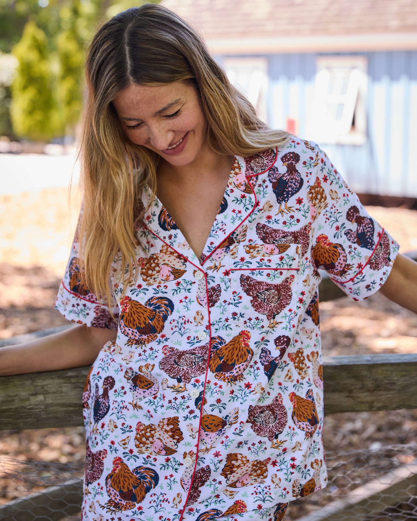 Close-up of a person wearing the floral chicken-print short pajama shirt with contrasting piping and buttons.