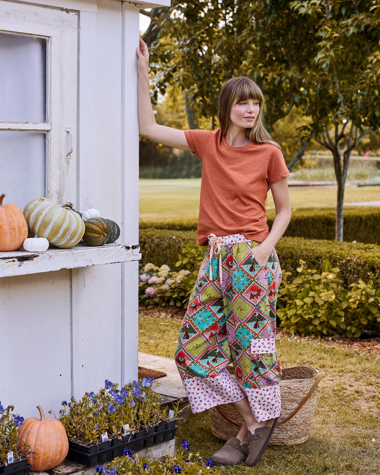 Full-length view of a person wearing cropped printed pants with contrasting cuffs and side pockets outdoors.