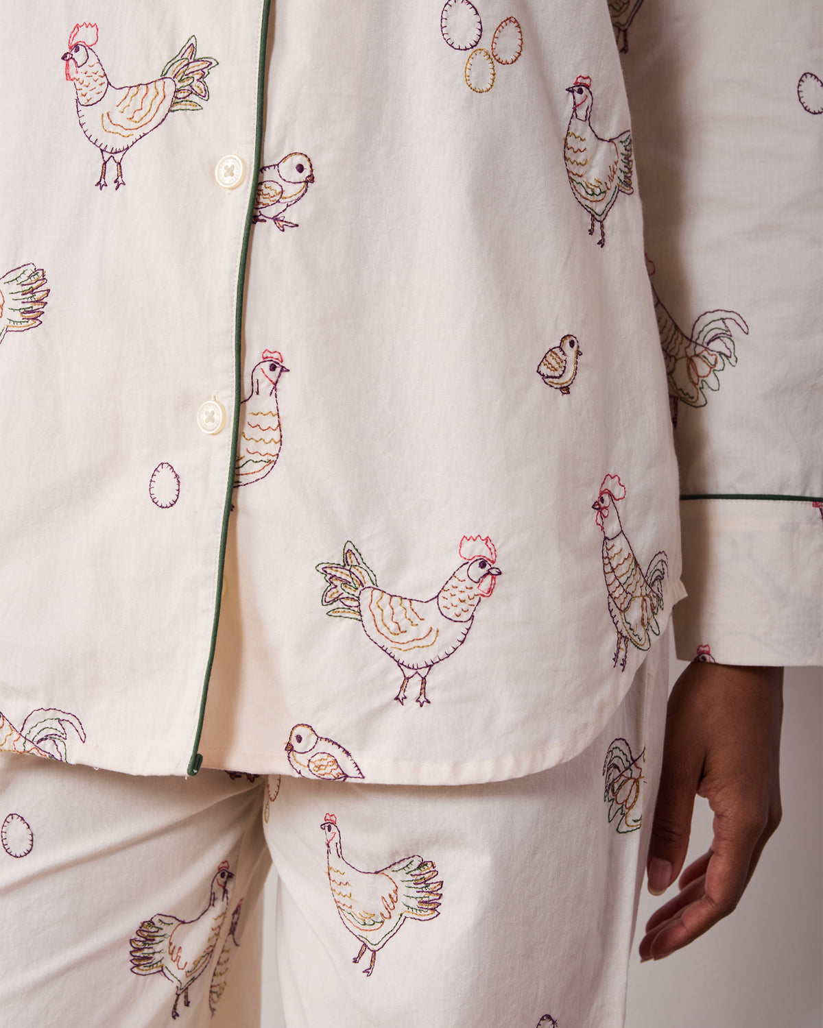 Close-up of the Embroidered Hens pajama top and pants showing hen, chick, and egg embroidery, buttons, and green piping.