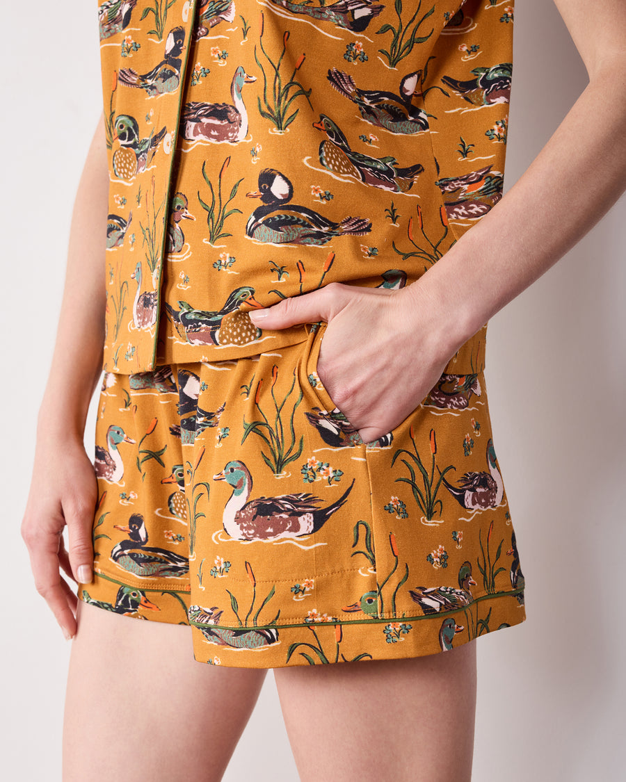 Close-up of the mustard Duck Pond short pajama set showing the printed top hem, matching shorts, and side pocket.