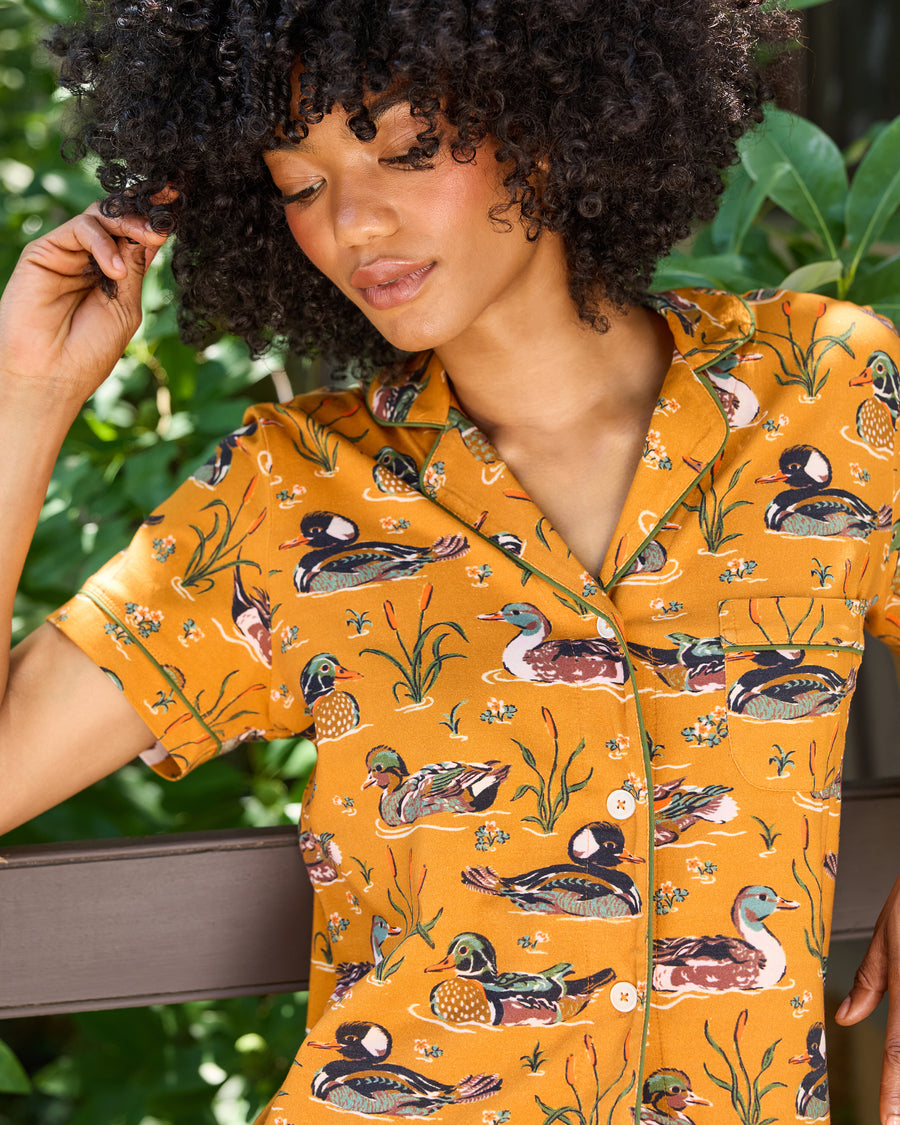 Close-up of the mustard Duck Pond short pajama top with a duck print, notched collar, piping, buttons, and chest pocket.