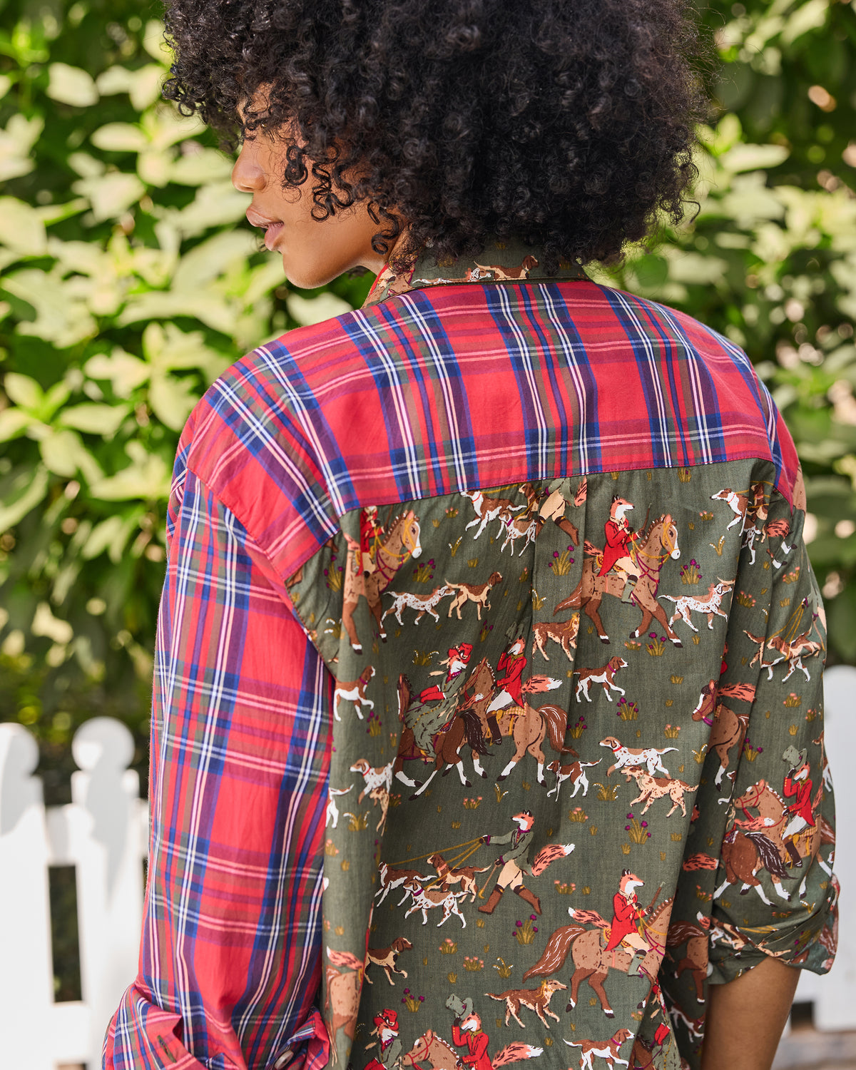 Back view of a button-down shirt with a red plaid yoke and sleeves and a green fox-and-hounds print across the lower back.