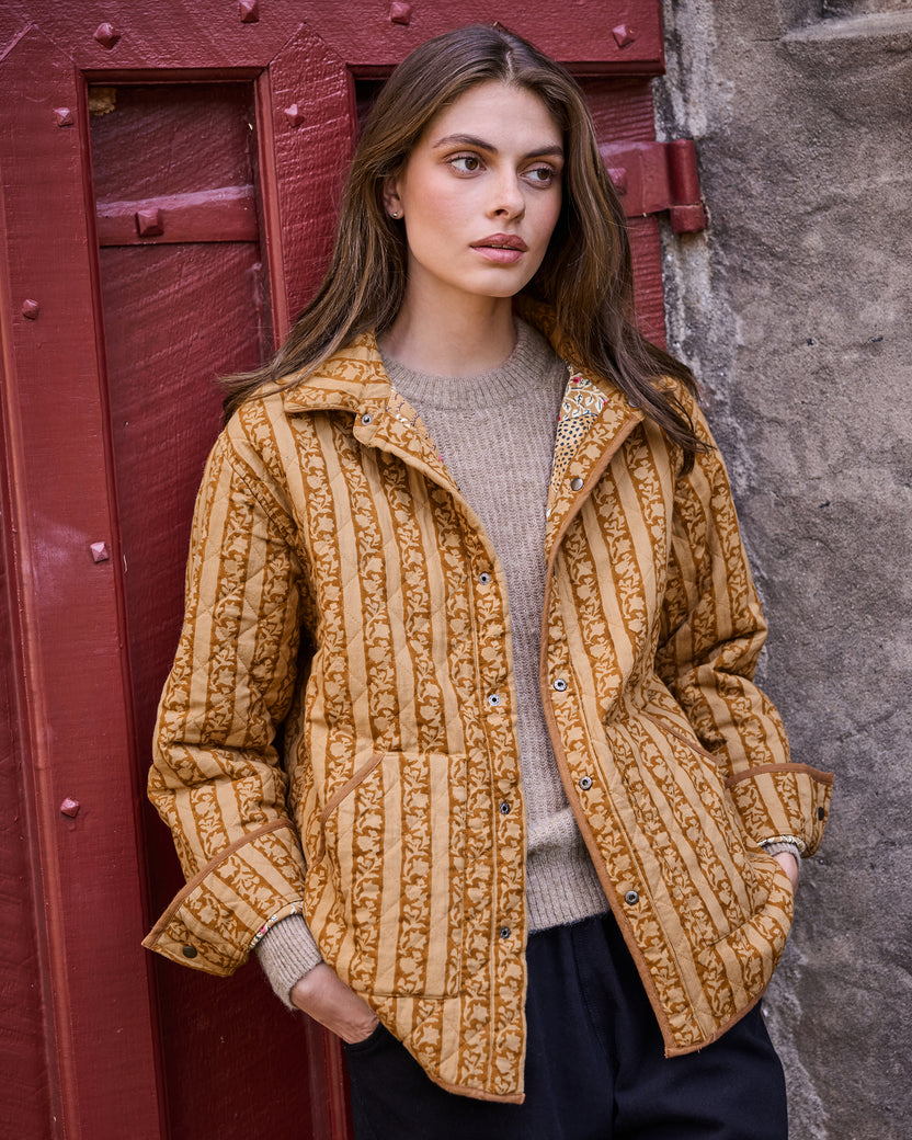 Model wearing the mustard quilted jacket with vertical botanical stripes, front view.