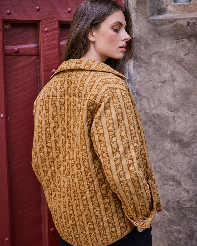 Mustard quilted jacket shown from the back with vertical botanical stripes.