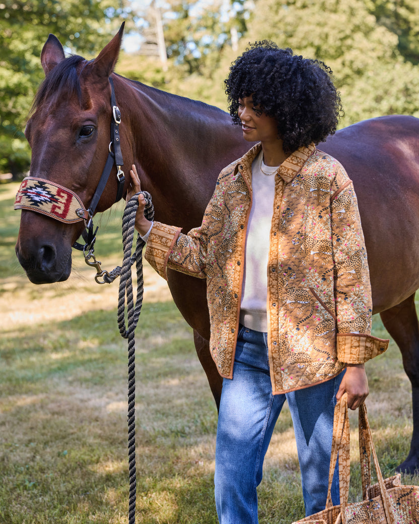 Model wearing the Garden Stripe reversible quilted jacket with jeans and holding a horse's lead rope.