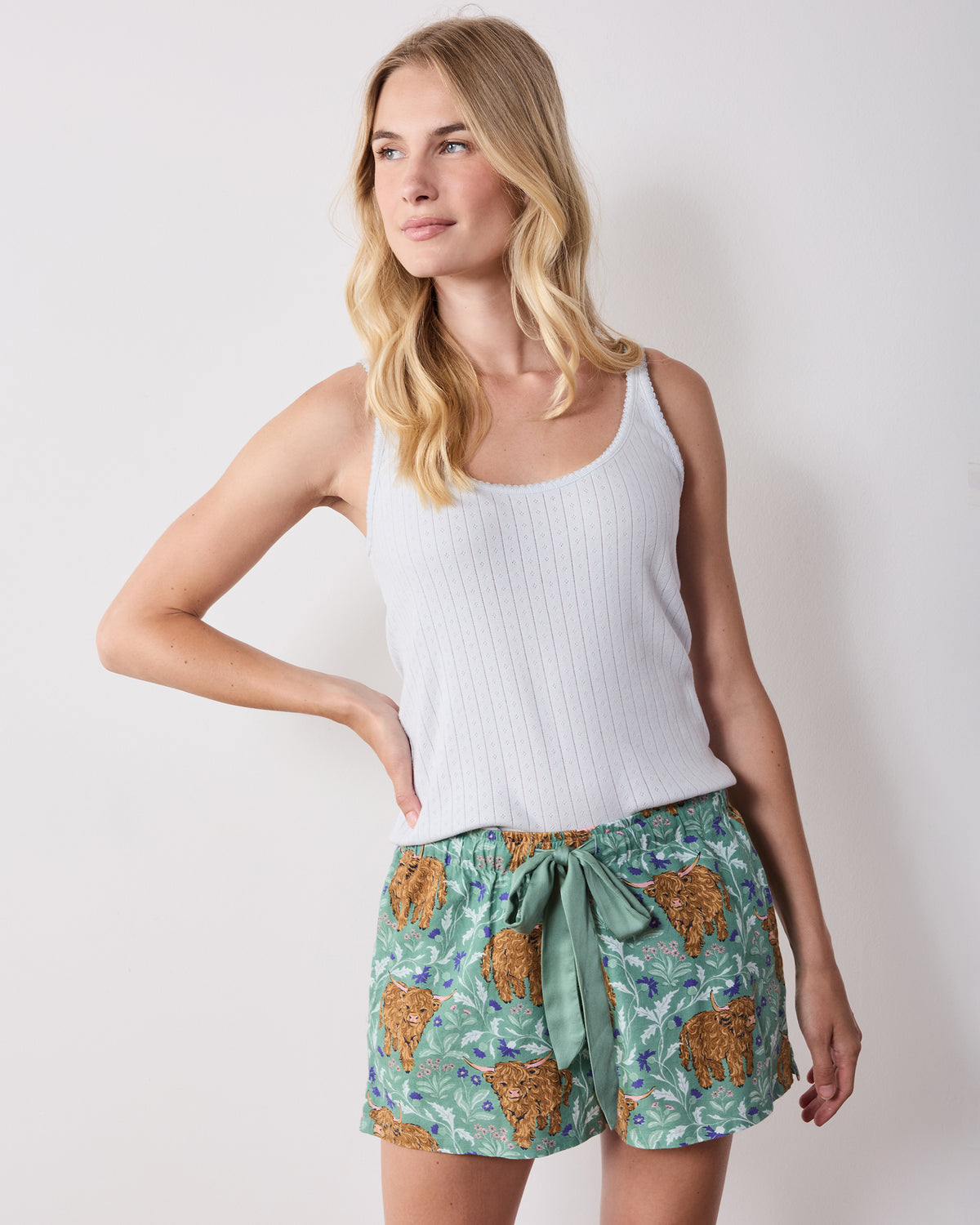 Model wearing green Highland cow-print pajama shorts with a white sleeveless top