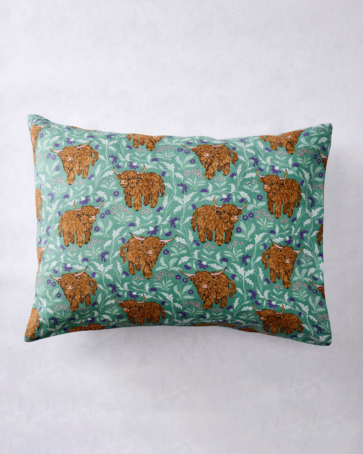 Full view of a standard pillowcase with repeated Highland cow and botanical print in the Soft Thistle colorway.