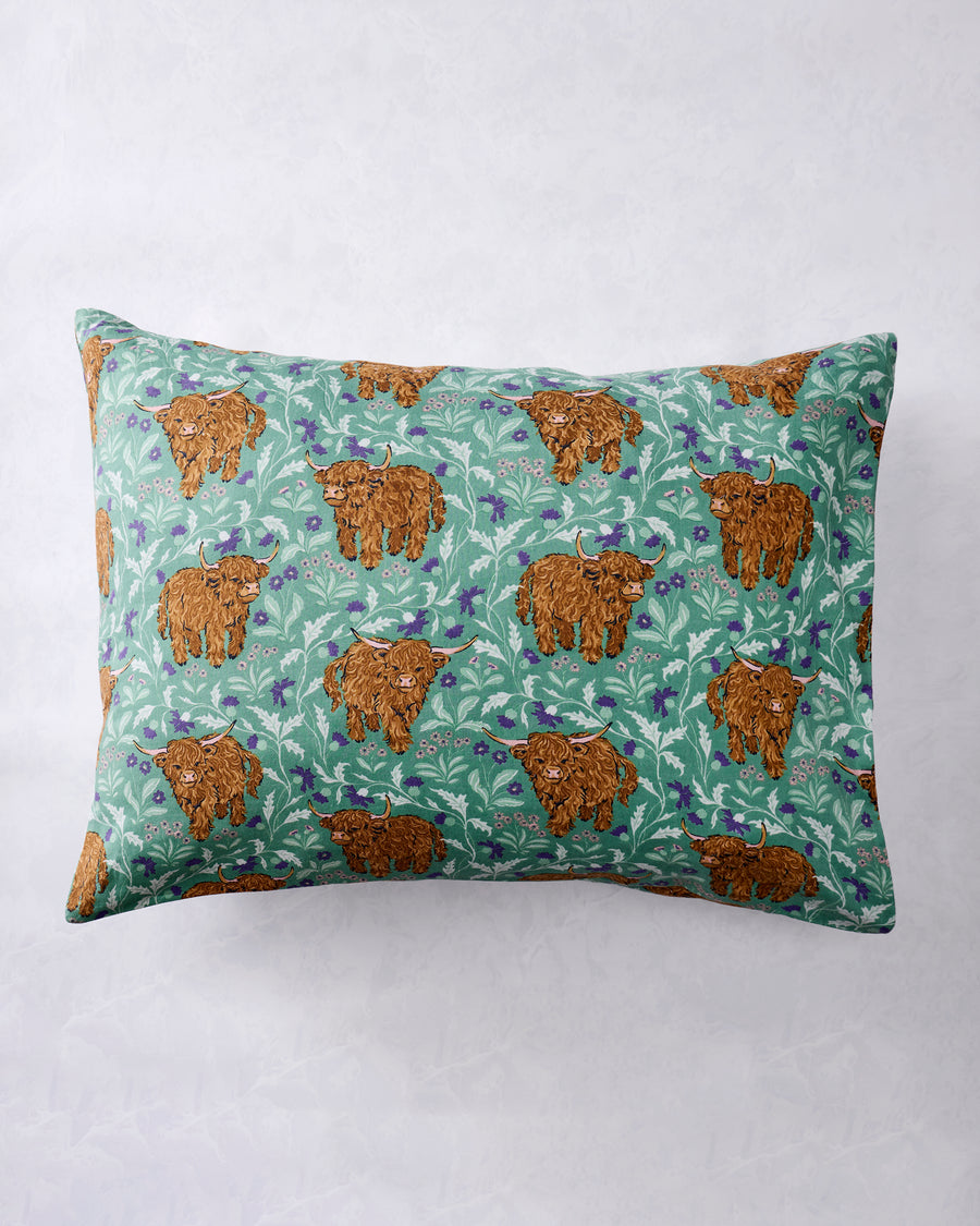 Full view of a standard pillowcase with repeated Highland cow and botanical print in the Soft Thistle colorway.