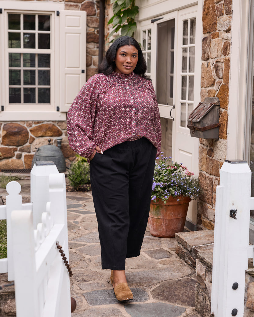 Full-length front view of the patterned Aspen blouse styled with black trousers.