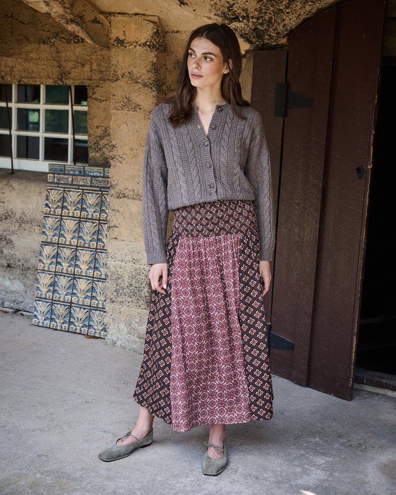 Front view of the patterned Coraline midi skirt styled with a gray cardigan.