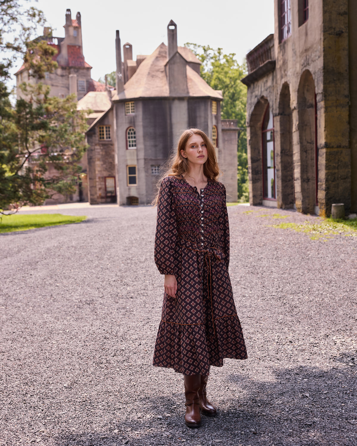 Full-length front view of the patterned Shay midi dress in a courtyard.