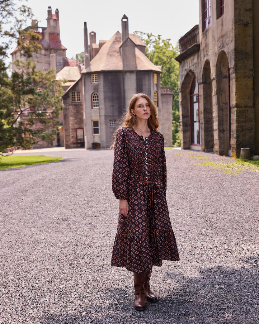 Full-length front view of the patterned Shay midi dress in a courtyard.