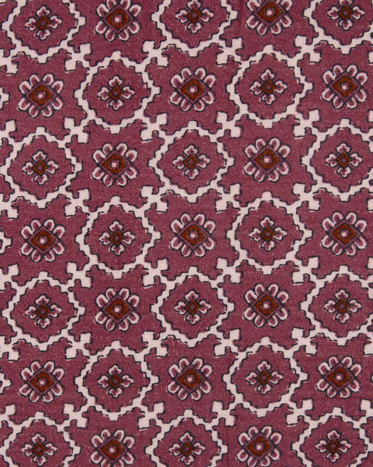 Close-up of mauve fabric with repeating geometric floral motifs in white, pink, and brown.