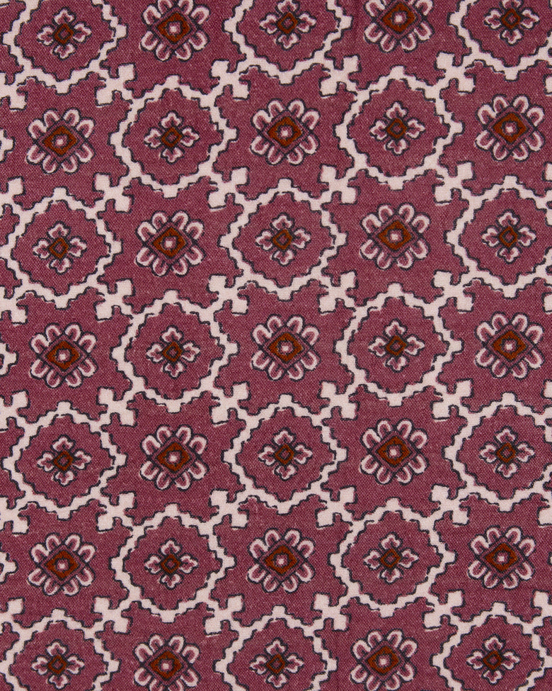 Close-up of mauve fabric with repeating geometric floral motifs in white, pink, and brown.