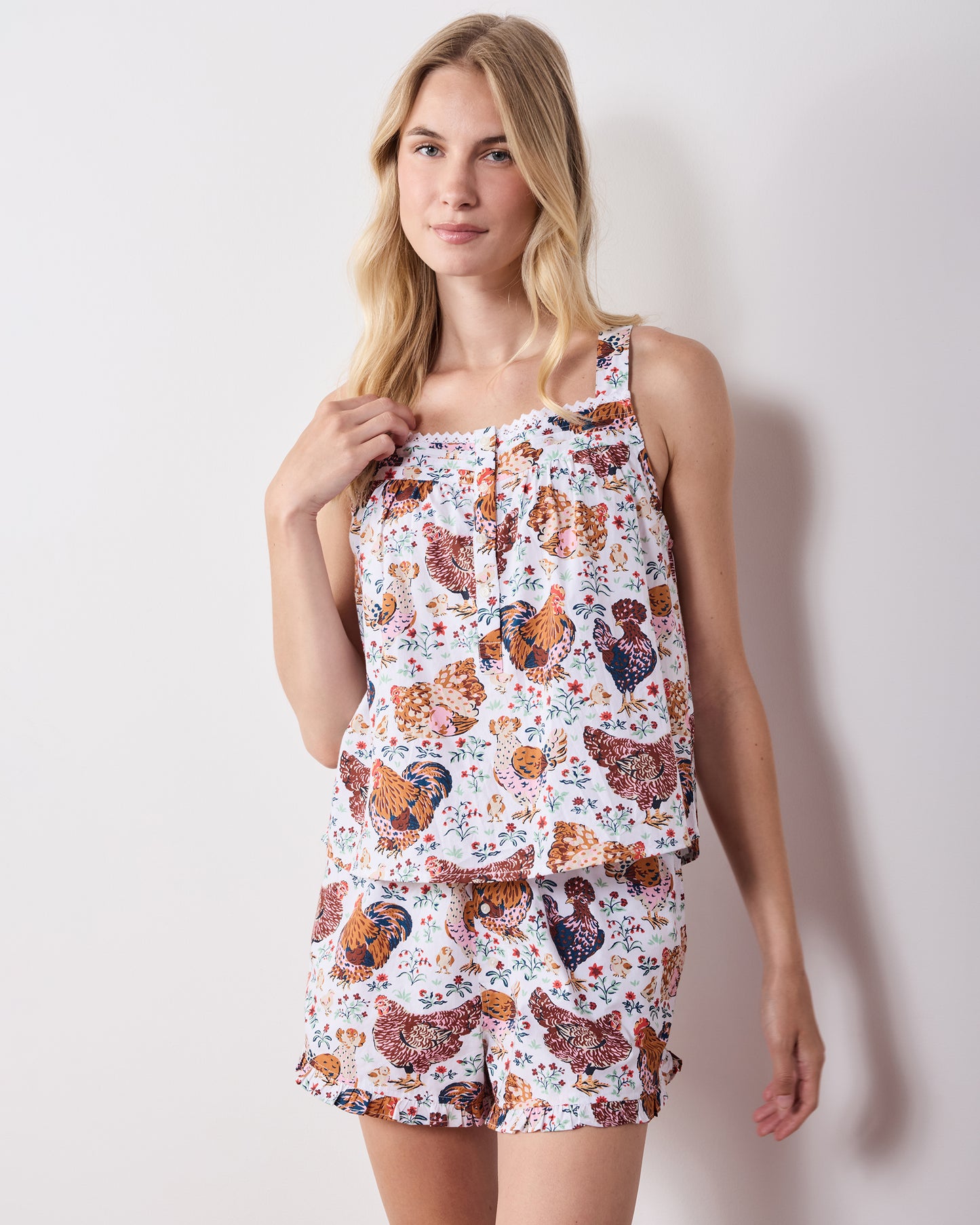 Full view of a model wearing the matching chicken-print camisole and ruffled shorts short pajama set.